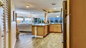 A modern kitchen with wooden cabinets, a large island, and a refrigerator. - Land's End 8-301 Beach Front (Treasure Island)