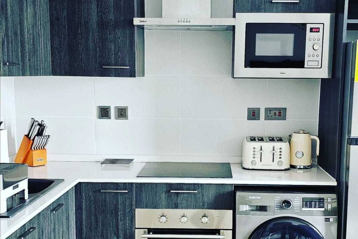 A modern kitchen with a built-in oven, microwave, and washing machine.
