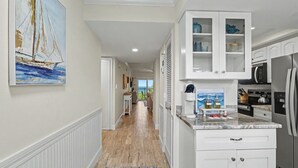 Eine Küche mit weißen Schränken, einer Arbeitsplatte mit Kaffeemaschine und Blick ins Freie.