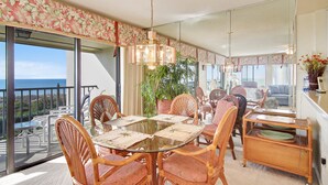 A dining area with a glass table, wicker chairs, and a view of the ocean. - Land's End 8-401 Beach Front (Treasure Island)