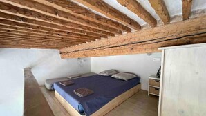 Ein kleines Schlafzimmer im Loft-Stil mit schrägem Dach, einem Einzelbett und einem Holzschrank.