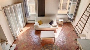 Ein gemütlicher, kompakter Wohnbereich mit einem weißen Sofa, einem kleinen Tisch und einem gemusterten Teppich.