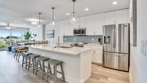 Une cuisine moderne dotée d’un grand îlot central, d’appareils électroménagers en acier inoxydable et de tabourets de bar.