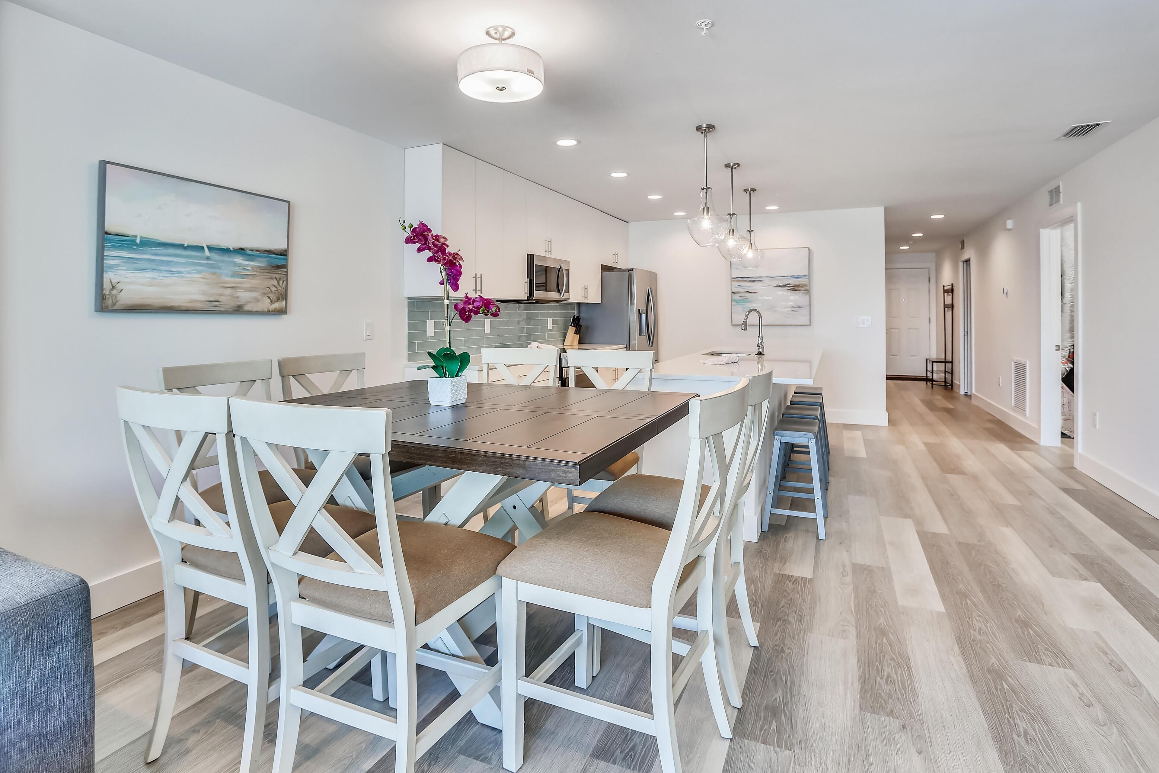 A modern kitchen with white cabinetry, a central island, and pendant lighting.