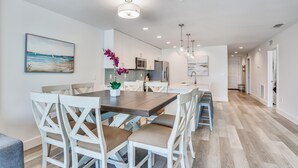 Une cuisine moderne avec des meubles blancs, un îlot central et des luminaires suspendus.