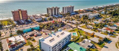 An aerial view of a coastal town with beachfront hotels, a large parking lot, and residential buildings.