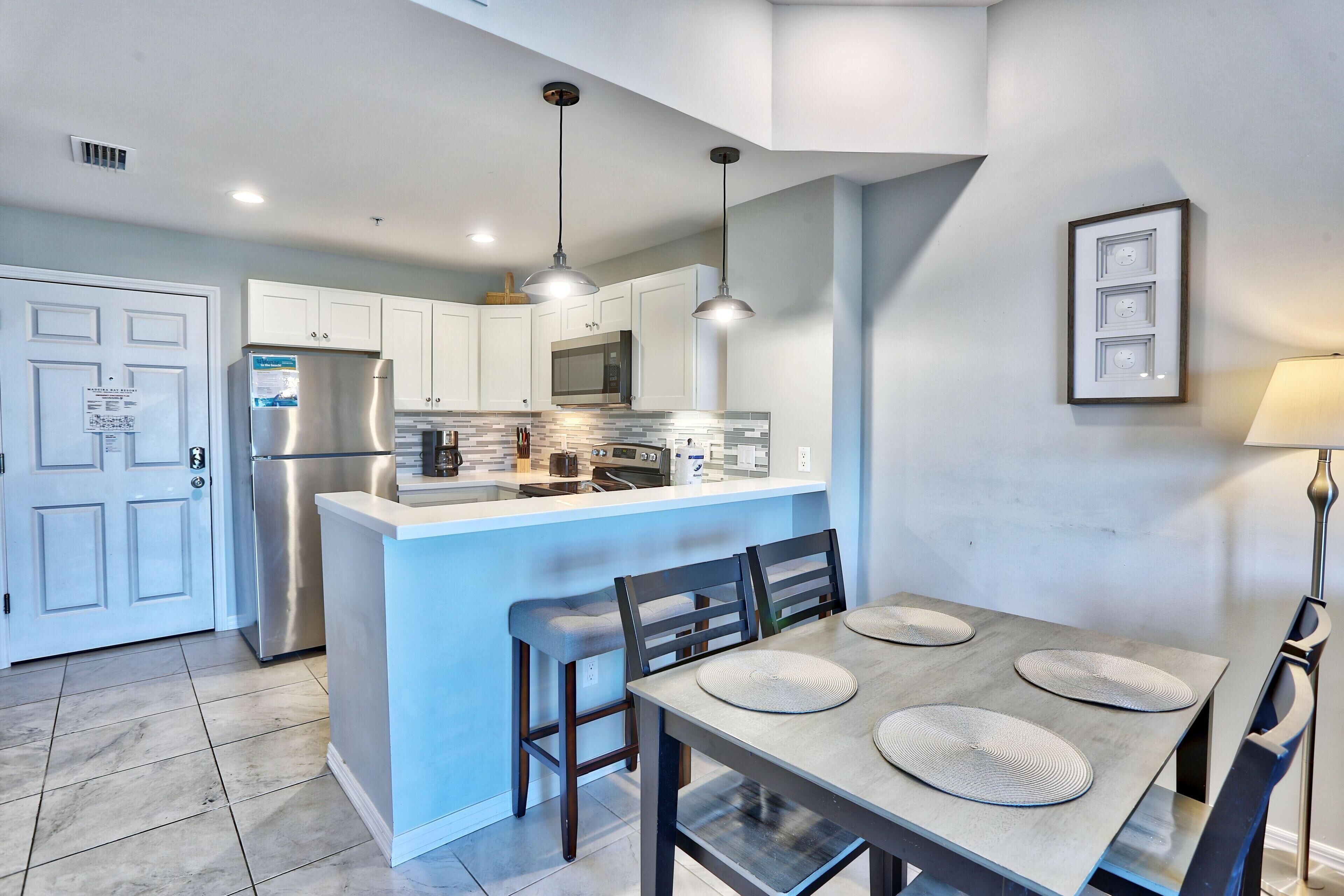 A modern kitchen with white cabinets, stainless steel appliances, and a central island with bar stools.