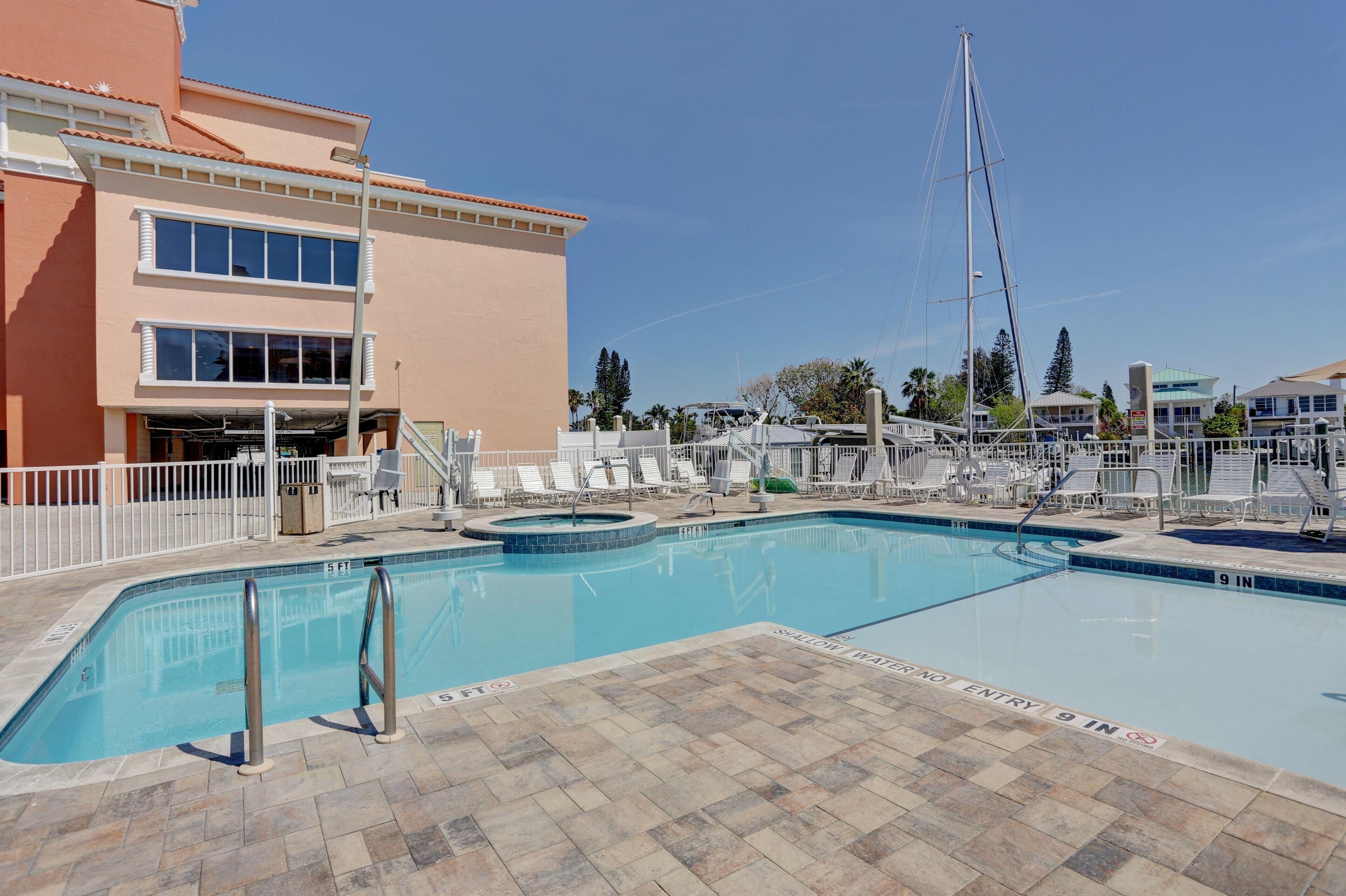A swimming pool with a tiled deck, a lifeguard tower, and a building with a red facade.