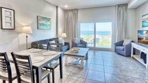 A modern living room with a dining area, large windows with a view of the sea, a ceiling fan, and a balcony. - Madeira Bay Resort I 1504 (Madeira Beach)