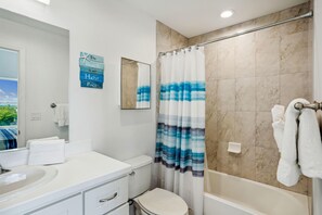 A bathroom with a shower curtain, a toilet, a sink, and a mirror. - Madeira Bay Resort I 1505 (Madeira Beach)