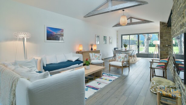Una sala de estar moderna con techo alto, tragaluces y ventanas amplias.