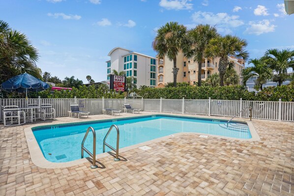 A swimming pool with a tiled deck, lounge chairs, and a fence. - Mariner's Pointe 202 (Indian Shores)