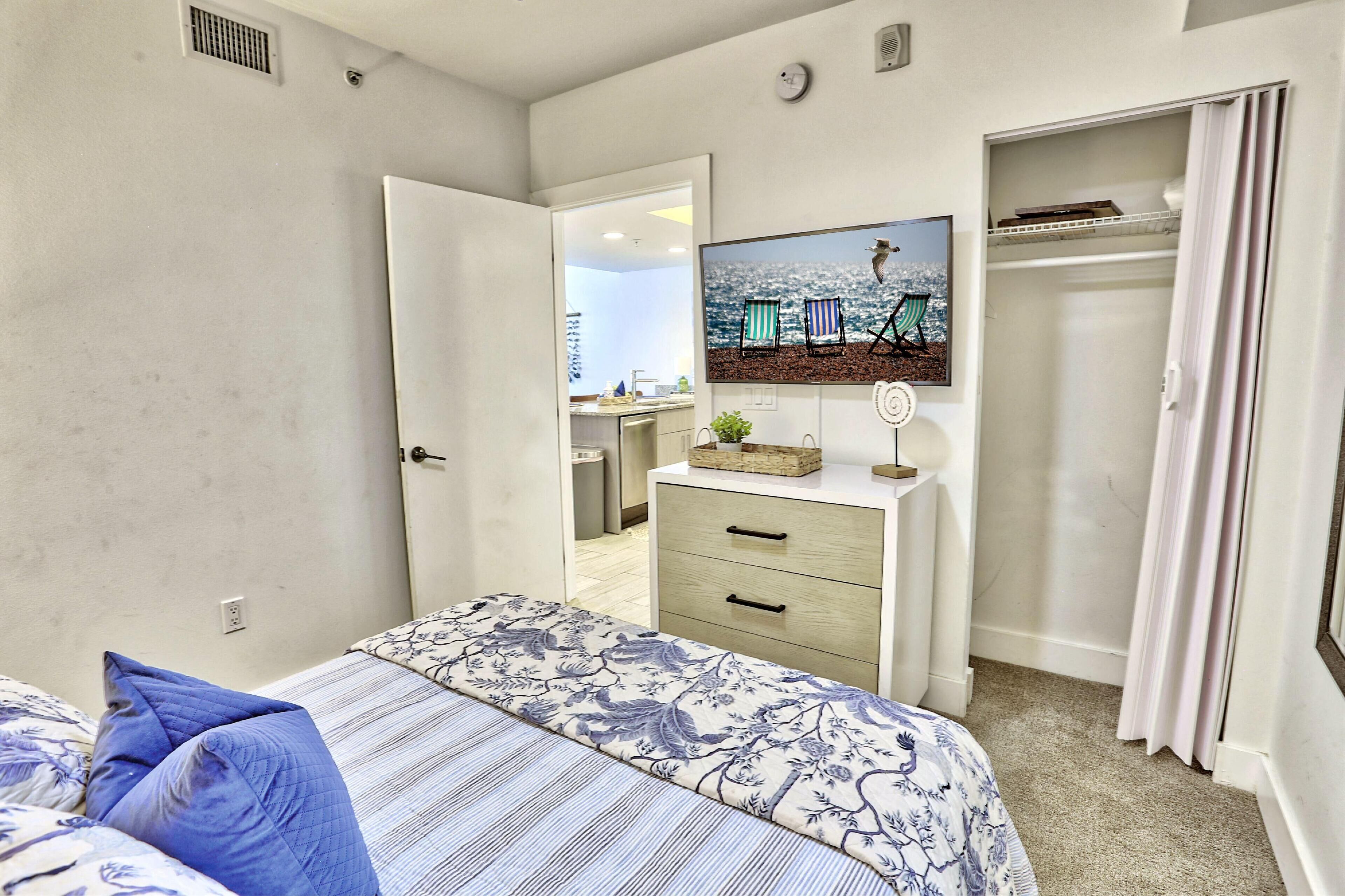 Une chambre à coucher comprenant un lit, une commode, un téléviseur et un placard.