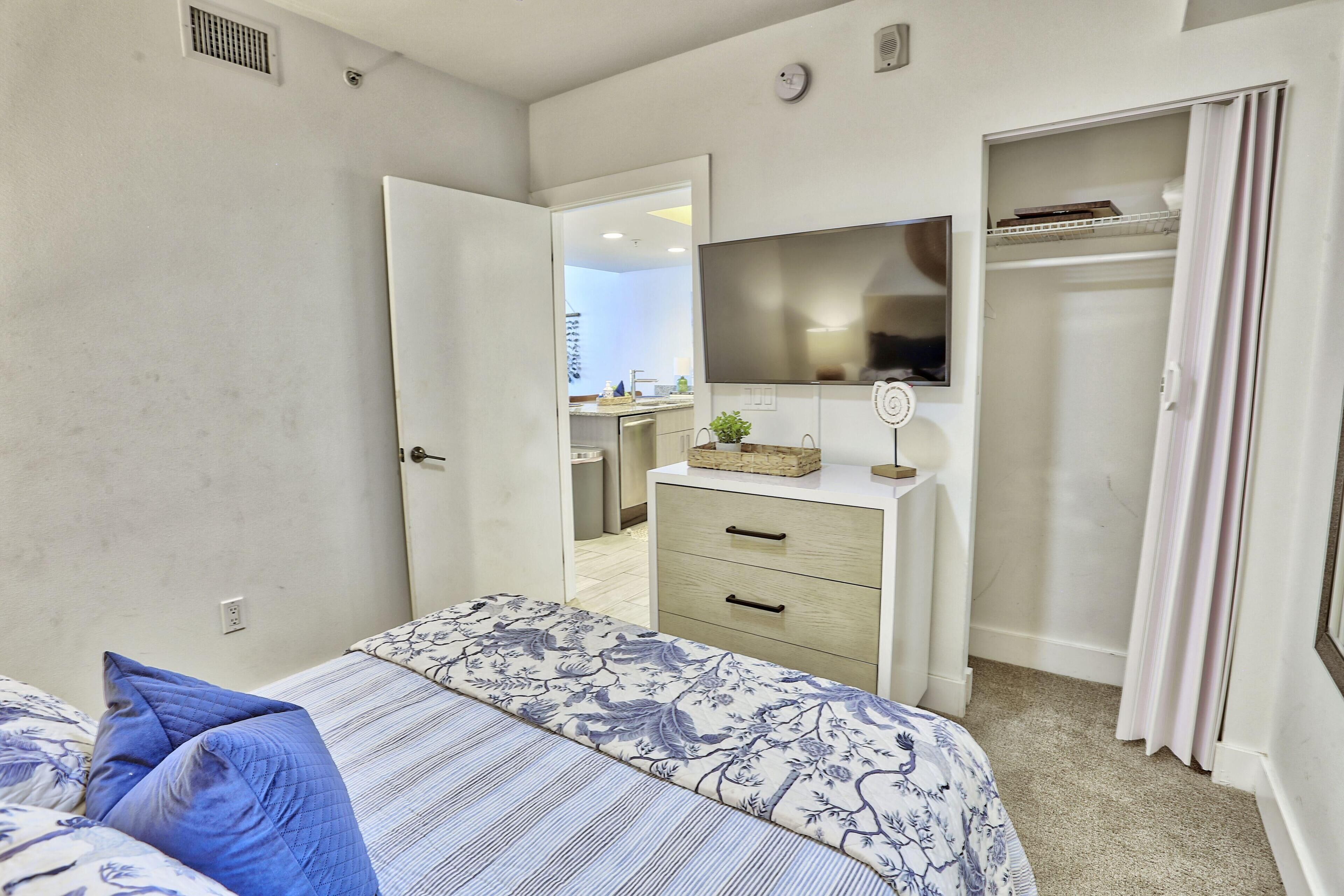 A bedroom with a bed, a dresser, a mirror, and a closet.