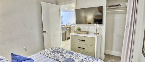A bedroom with a bed, a dresser, a mirror, and a closet.