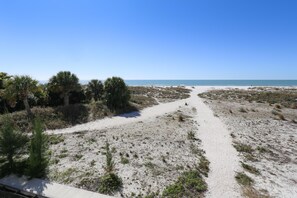 A beach path leading to the ocean with sparse vegetation and a clear sky. - Oceana 202 West (Treasure Island)