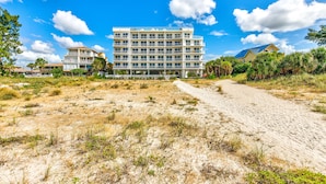 Ein mehrgeschossiges Hotel mit Innenhof, umgeben von trockenem Gras und Sand.