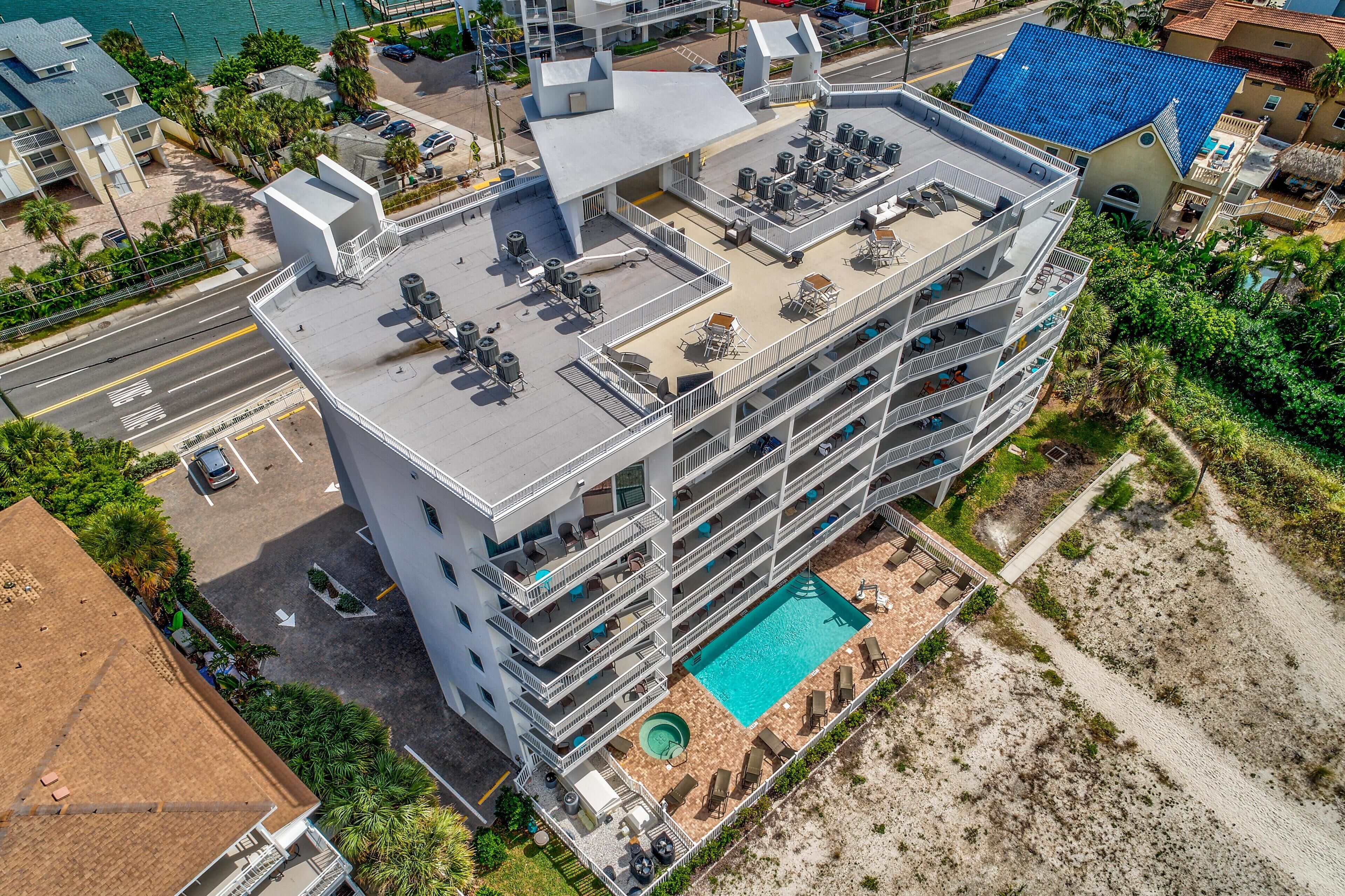 Ein Mehrstöckiges Hotel mit Pool auf dem Dach, Balkonen und einer Strandlage.