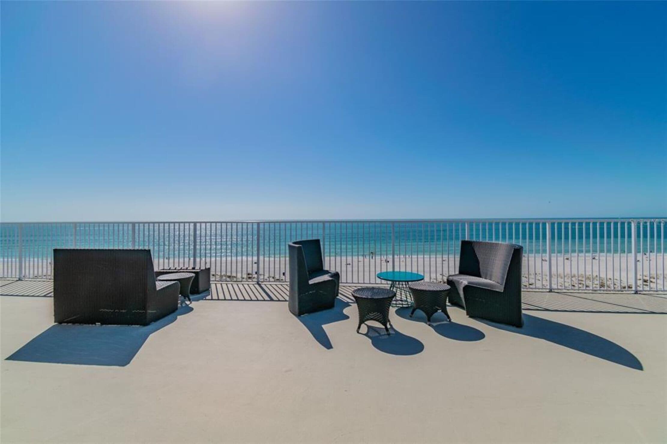 Eine Terrasse am Strand mit Gartenmöbeln und Blick auf das Meer.