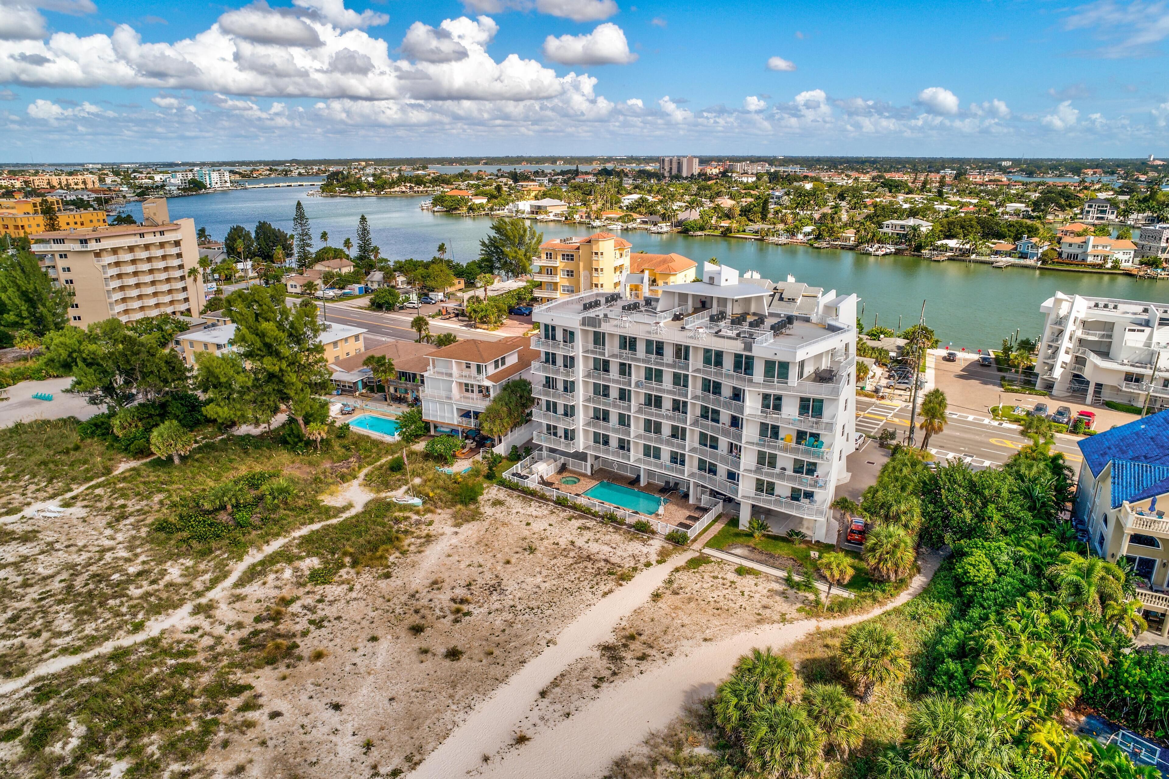 A multi-story hotel with a pool, located near a beach and water body.