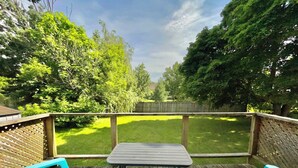 A wooden deck with a table and chairs, surrounded by a wooden fence and lush greenery. - Mountain View Suite - Sleeps 6
 (St. Catharines)