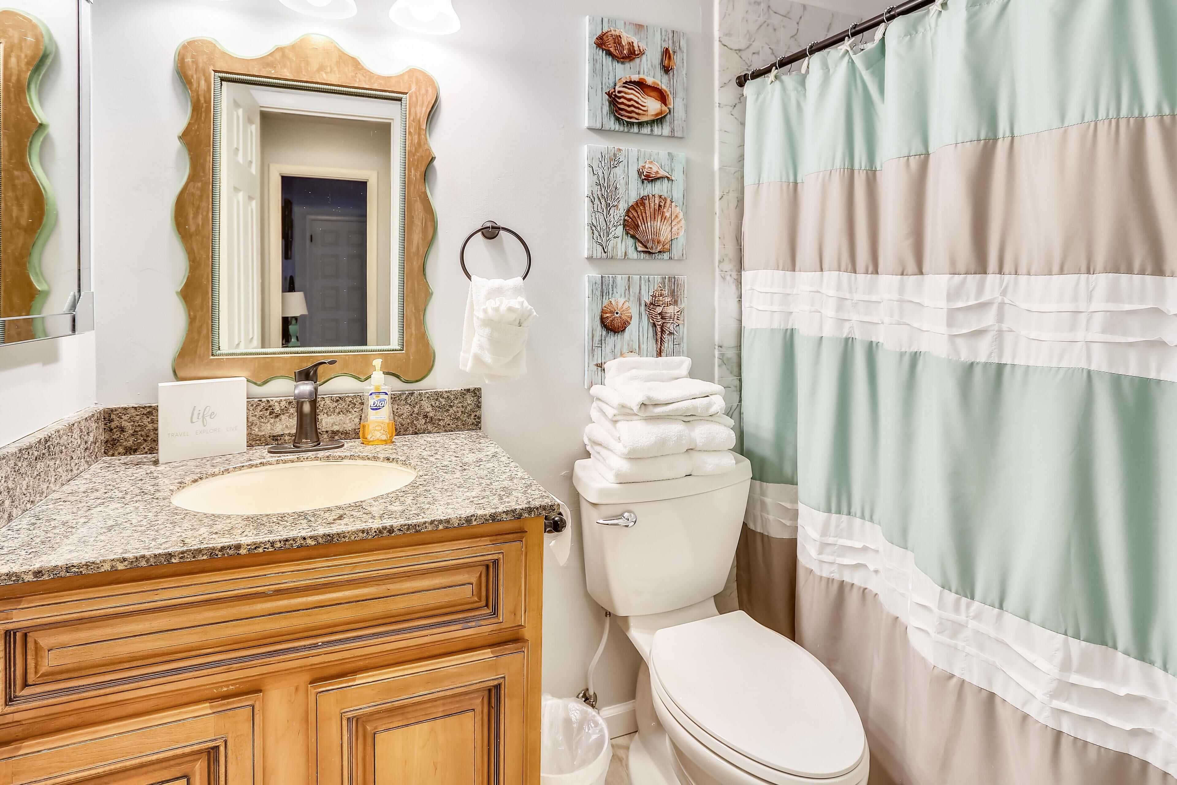 A bathroom with a sink, mirror, toilet, and shower curtain.