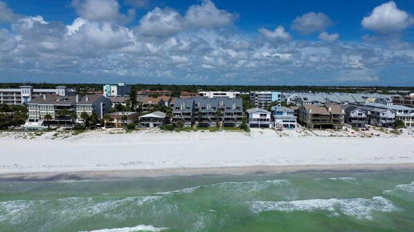 A beachfront hotel with multiple buildings, a sandy beach, and ocean waves.