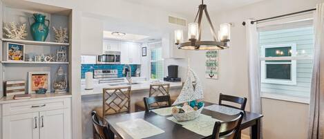A dining area with a dark wooden table, white cabinets, and a decorative wall piece.