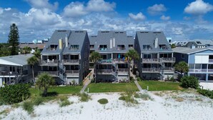 A beachfront hotel with multiple-story buildings, balconies, and a sandy beach area. - Pelican Pointe 2C (Indian Shores)