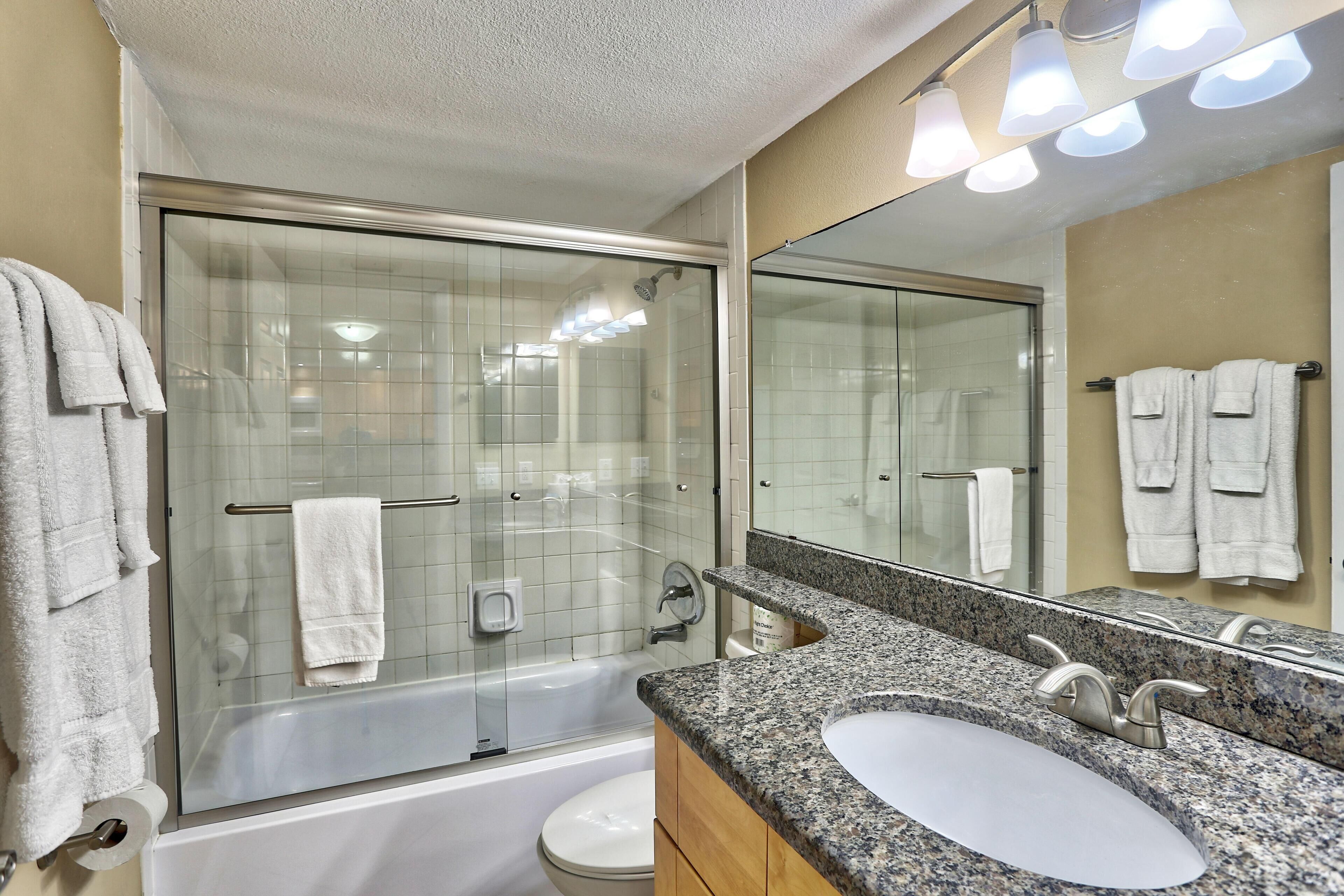Un bagno moderno con doccia vetrata, una vasca freestanding e un lavabo su piano in granito.