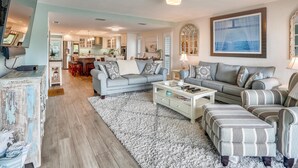 Un salon spacieux avec un canapé gris, une table basse et un grand tapis.