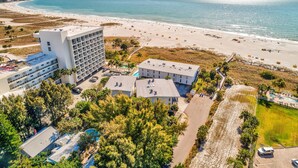 Luchtbeeld van een kusthotel met meerdere gebouwen, een strand en een zwembad.