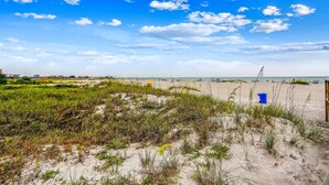 Een strand met duinen, een heldere lucht en een verre horizon van de zee.