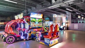 Une salle d’arcade lumineuse, dotée de différents jeux, dont un jeu « NERF » particulièrement visible.