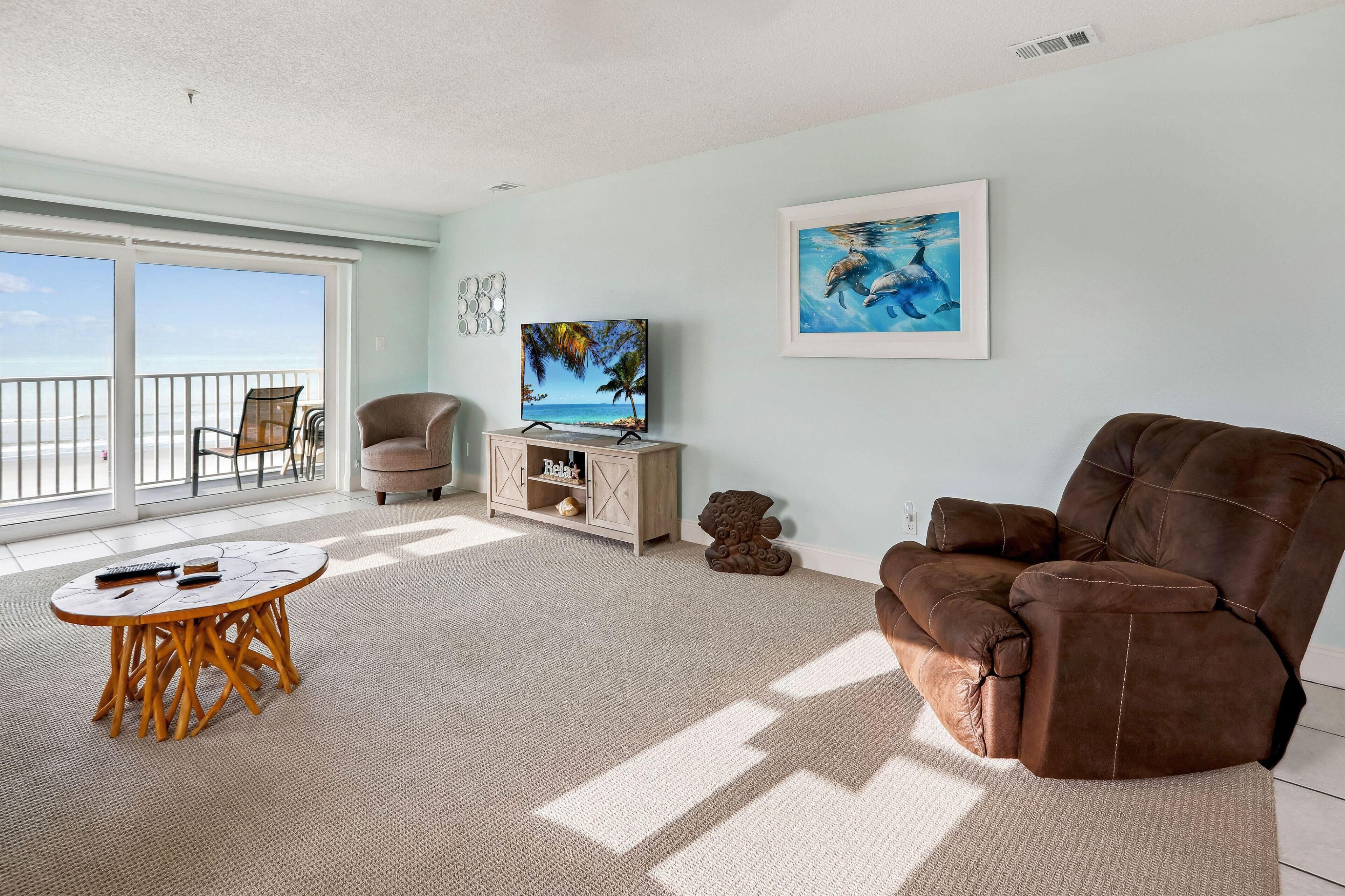 A living room with a large window, a sofa, a TV, and a small table.