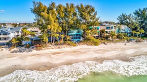 A beachfront property with multiple buildings, a sandy beach, and waves crashing onto the shore. - Serenity By The Sea (Treasure Island)