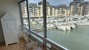 A balcony with a view of a marina and residential buildings. - Appartement Les Lupins vue Port (Courseulles-sur-Mer)