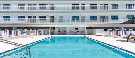 Ein Hotel mit Schwimmbad, mehreren Balkonen und einer Sonnenterrasse.