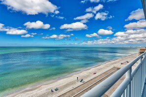 Een strand met helder turquoise water, een zandstrand en enkele mensen.