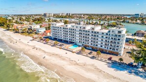 Un hotel sulla spiaggia con diversi piani, una piscina e una zona spiaggia.