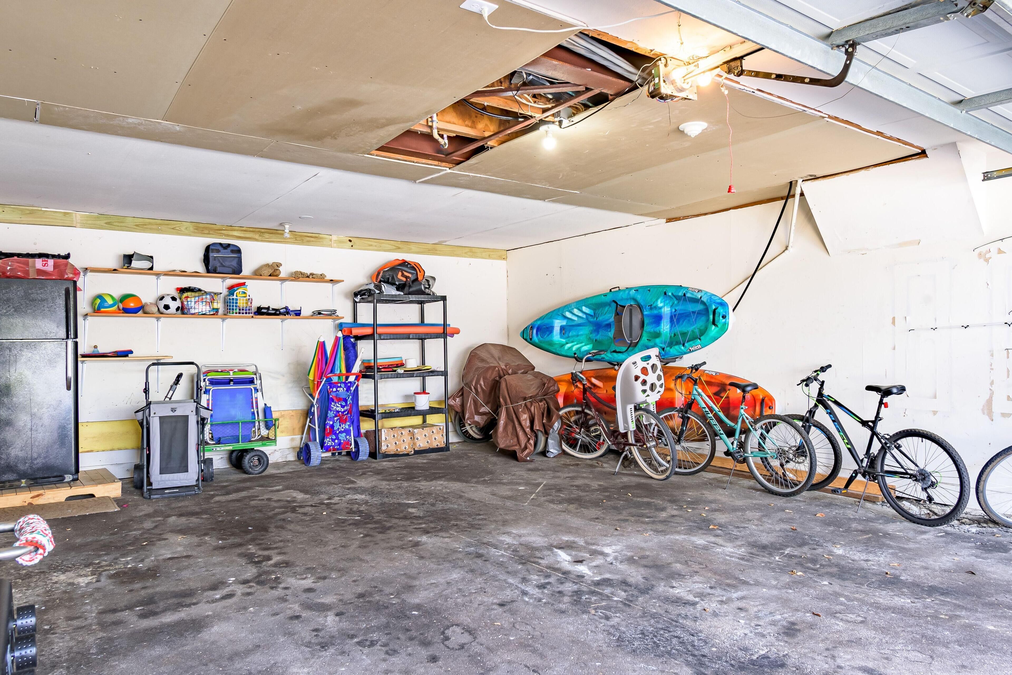 A garage with bicycles, a kayak, and various sports equipment.
