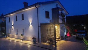 A two-story house with a garage, exterior lighting, and a small balcony.