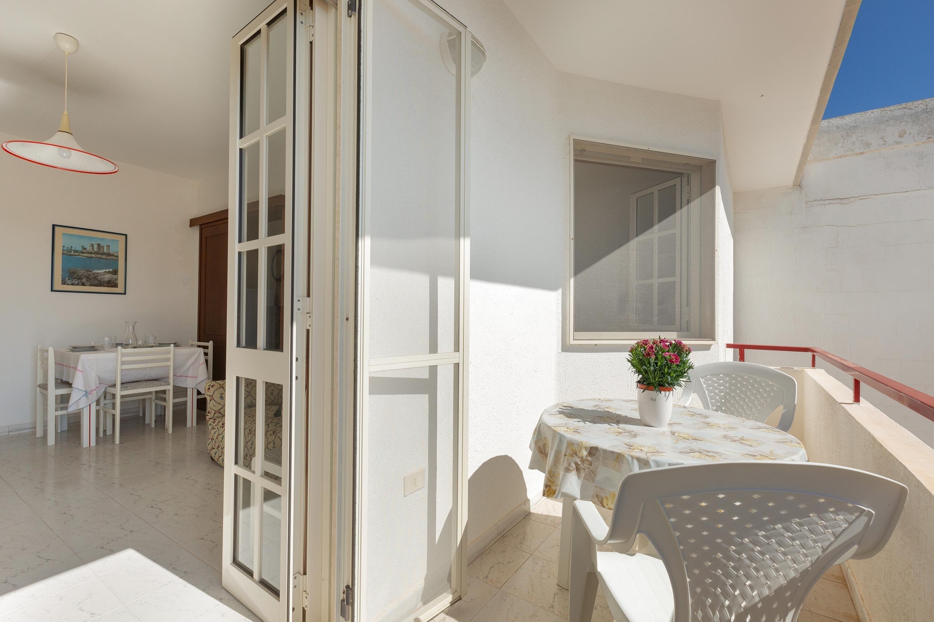 Un balcón con una mesa y sillas, una planta en maceta y un comedor con mesa y sillas.