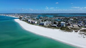 A coastal town with a long sandy beach, clear blue waters, and a mix of residential and commercial buildings. - Sunset Vistas 211n (Treasure Island)