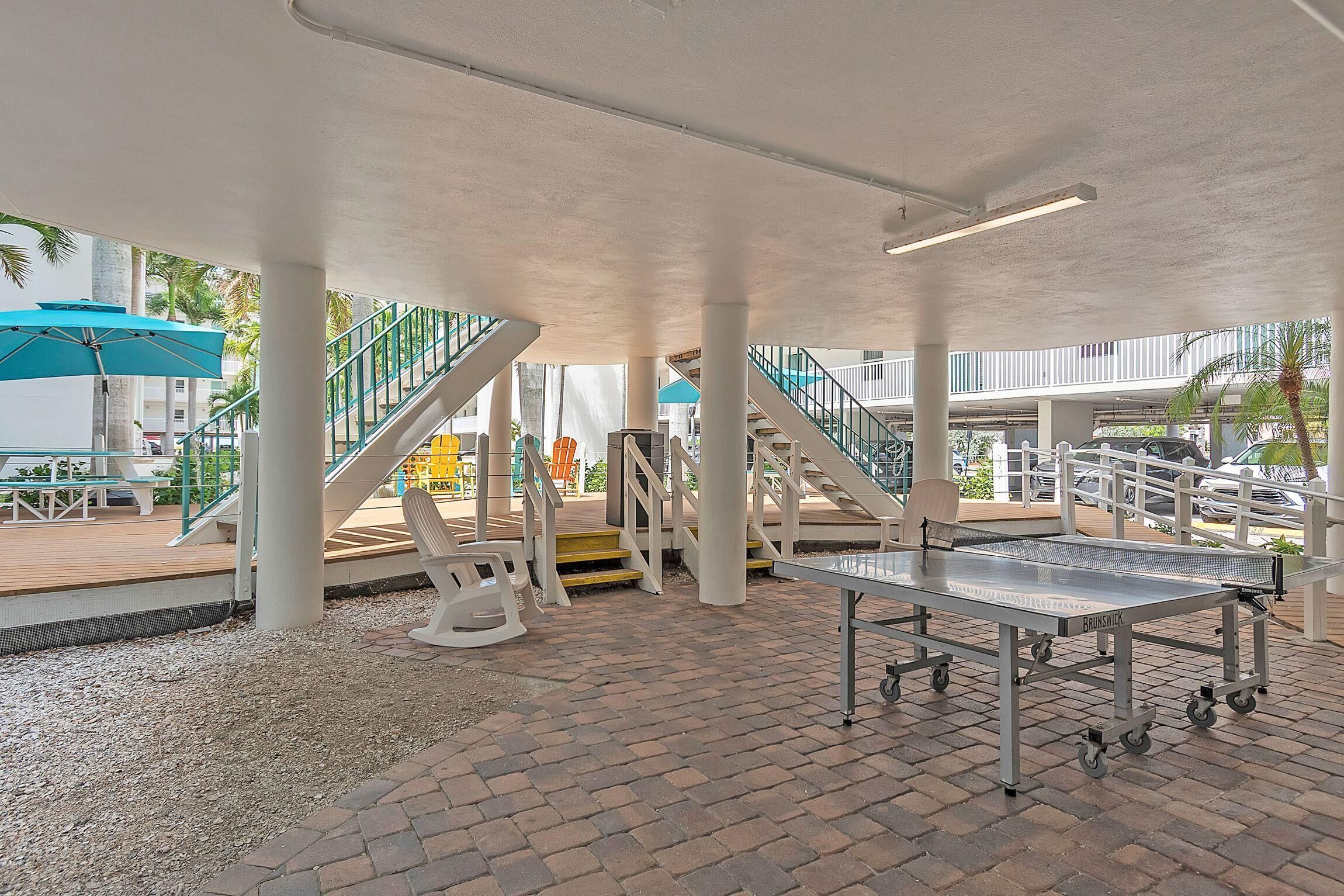 An outdoor area with a ping pong table, seating, and a staircase.