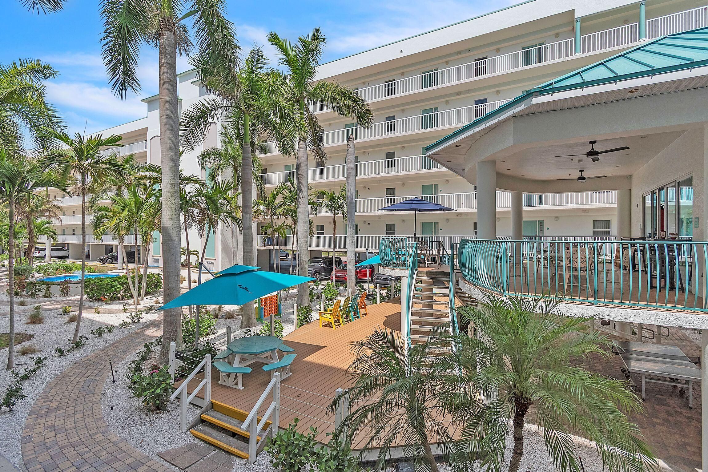 A resort with multiple balconies, palm trees, outdoor seating, and a pool.