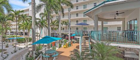A resort with multiple balconies, palm trees, outdoor seating, and a pool.