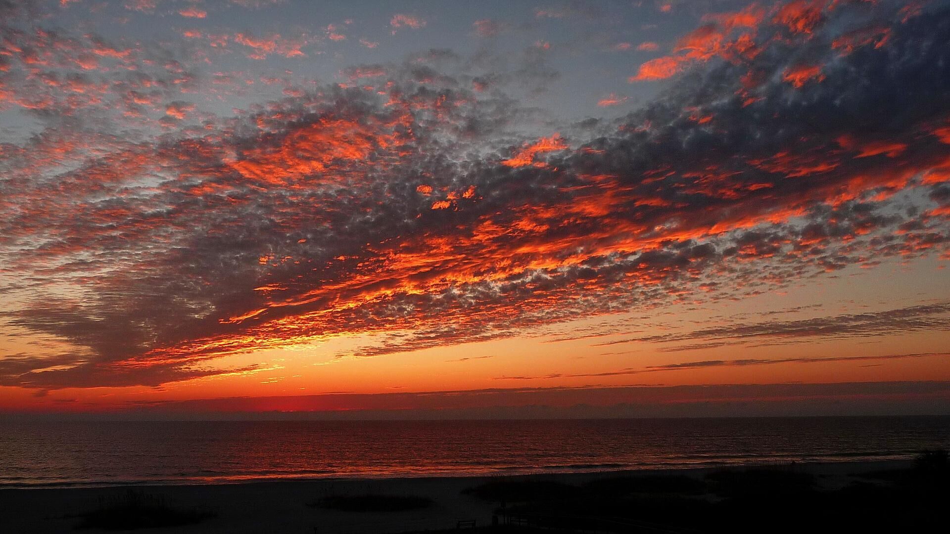 Un atardecer sobre el océano, con una playa en primer plano.