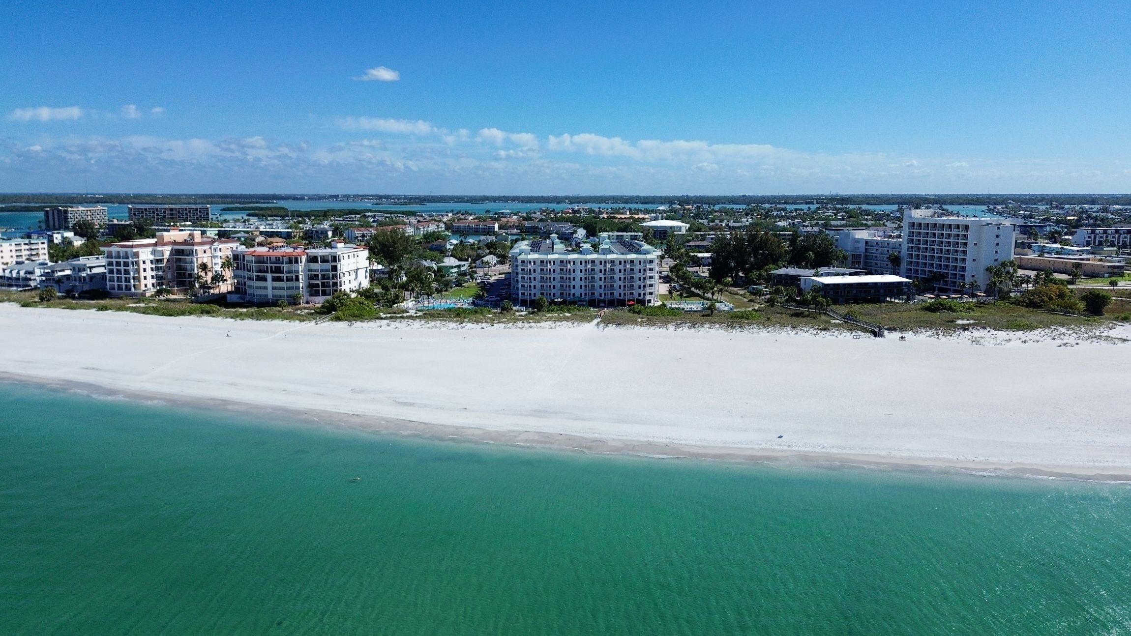 A coastal hotel with multiple buildings, a beach, and a clear view of the ocean.