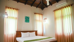 A bedroom with a wooden bed, beige curtains, a green throw, and a ceiling fan. - Villa Mandari (Dharga Town)